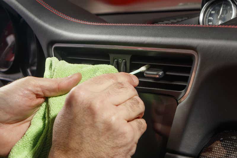 Dusting the car interior air conditioning vent with a swab 